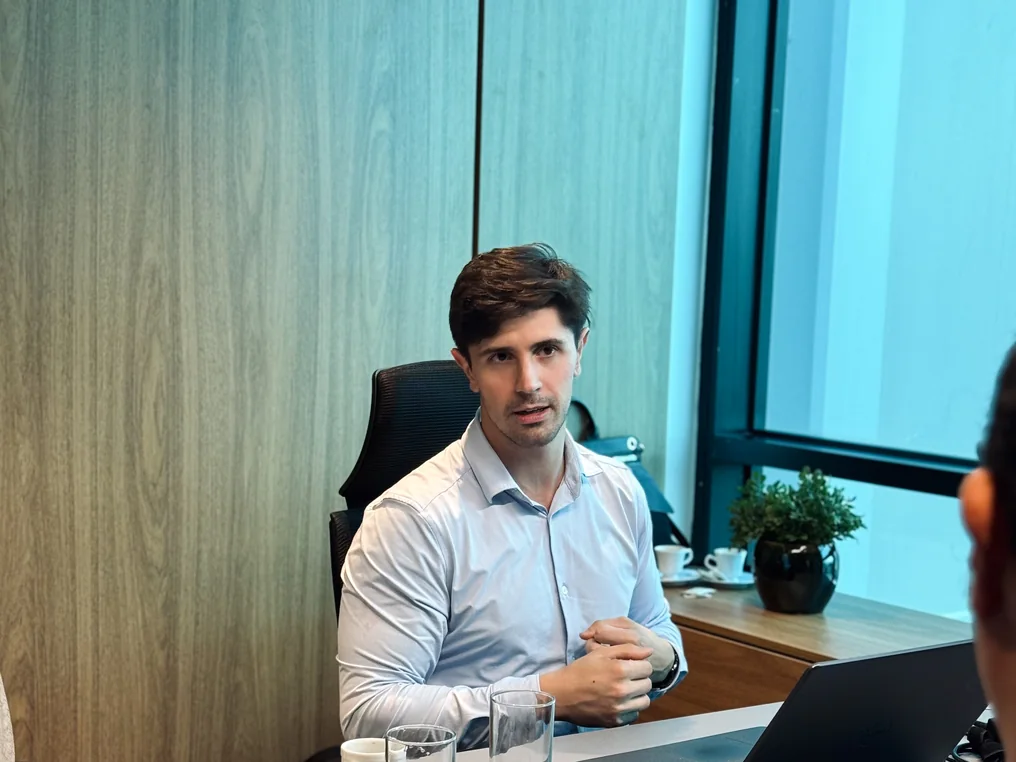 Consultor da Fato em reunião com o cliente, à mesa com notebook, em sala de vidro